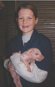 Sage Tokach posing with a newborn piglet