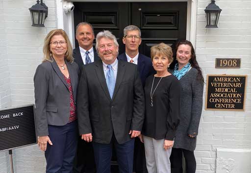 Drs Angela Baysinger, Bill Hollis, Harry Snelson, Mike Senn, Mary Battrell, and Abbey Canon standing in front of an exterior door labeled American Veterinary Medical Association Conference Center