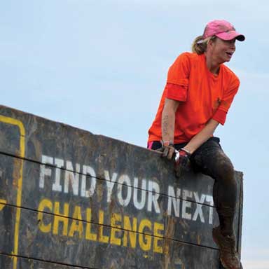 Dr. Baysinger climbing over a wall in an obstacle course