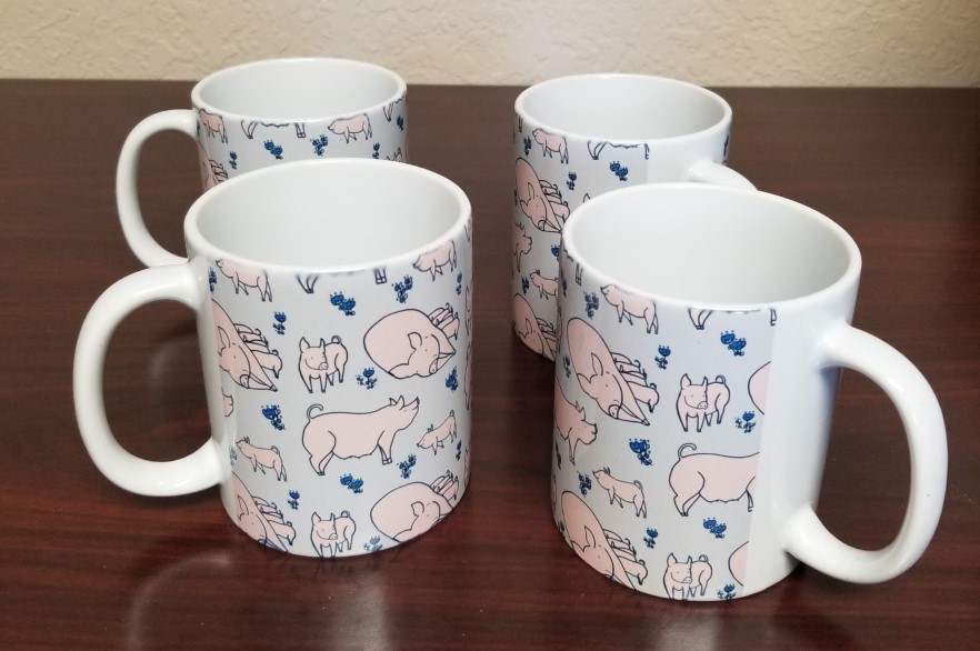 Four white coffee mugs with design of pink and blue pigs