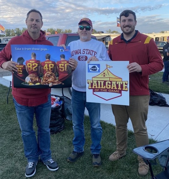 Three swine veterinarians holding signs promoting pork and Iowa State football.