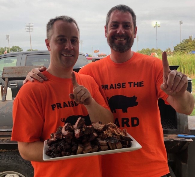 Aaron Lower and Clayton Johnson holding a plate of barbecue pork.